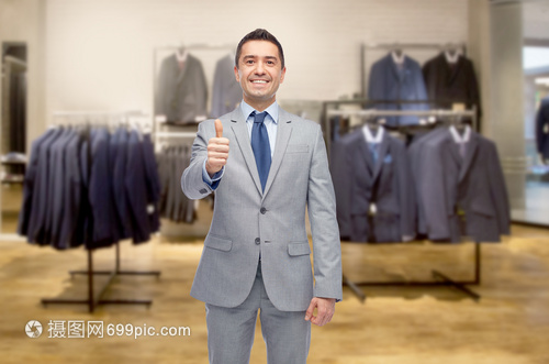 商业,人,男装,销售服装快乐的微笑商人穿着西装,服装店的背景上竖大拇指
